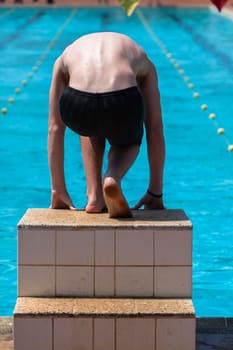 Swimming Gala race swimmer teenager boy on starting block crouched
