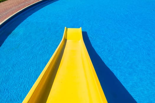 Swimming pool blue water yellow slide outdoors