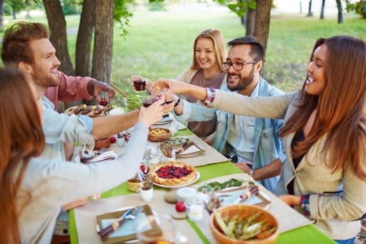 Happy friends cheering up at Thanksgiving party outdoors