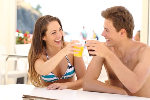 Friends toasting in summer vacation in a restaurant terrace on the beach
