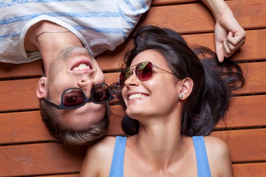 Happy young couple lying head to head on a wooden floor
