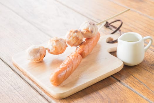 Squid ball and hotdog grilled on wooden plate, stock photo