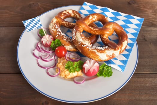 Bavarian vegetarian breakfast with two pretzels and obazda with plates on wooden boards