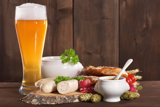 White sausage breakfast with sausages,pretzels,white beer and sweet mustard on wood substrate