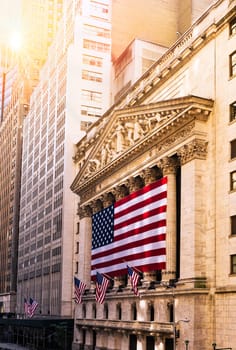 Famous Wall street and the building in New York, New York Stock Exchange with patriot flag