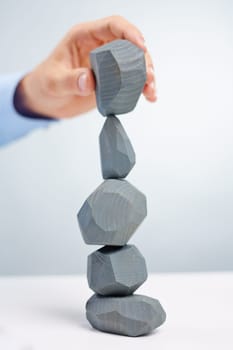 Businessman putting grey stone onto another one