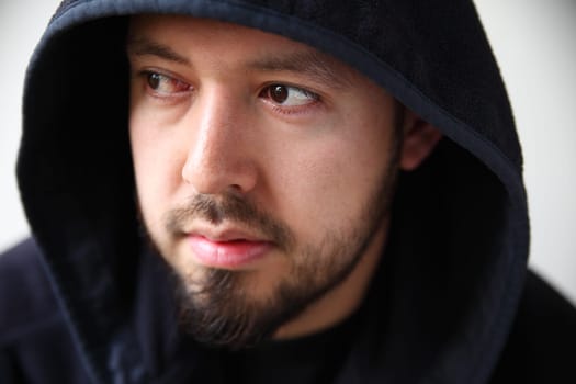attractive young man with dark eyes and beard in a black hooded jacket