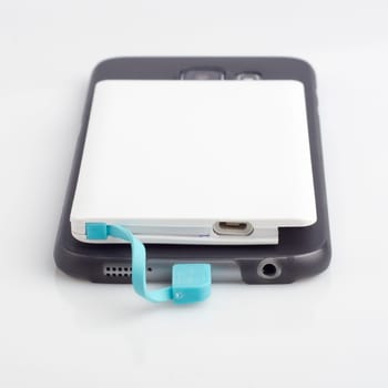 Charging a smartphone from powerbank on white table