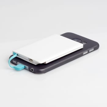 Charging a smartphone from powerbank on white table