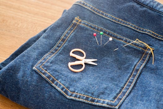 Needle with a thread through the jean, stock photo