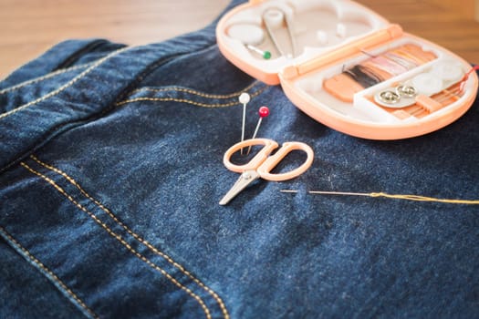 Needle with a thread through the jean, stock photo