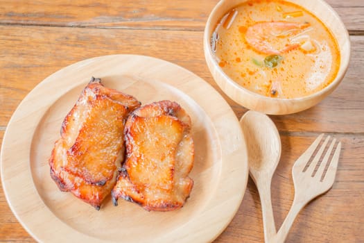 Chicken steak and spicy soup on wooden table, stock photo