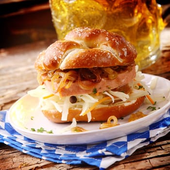 Tasty Bavarian meat loaf and cheese roll with traditional spicy beef and pork meat loaf with grated cheese on a crusty bun served with a tankard of beer in a tavern