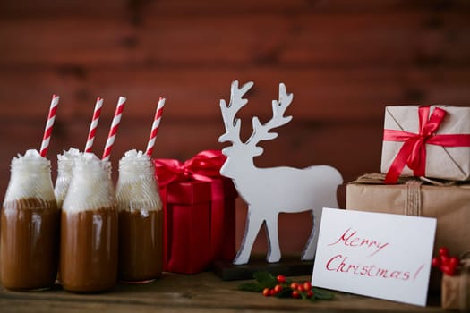 Toy deer, bottles with hot chocolate topped with whipped cream and giftboxes