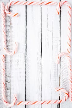 Several candy canes making frame over wooden background