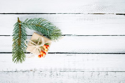 Gift in package and evergreen conifer branches over wooden background