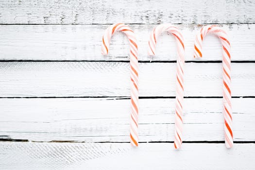 Three candy canes over wooden background