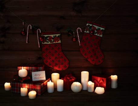 Christmas socks, sugar canes, toy bubbles, burning candles and giftboxes on wooden background