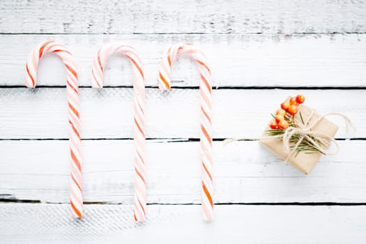 Candy canes and small package with gift over wooden background