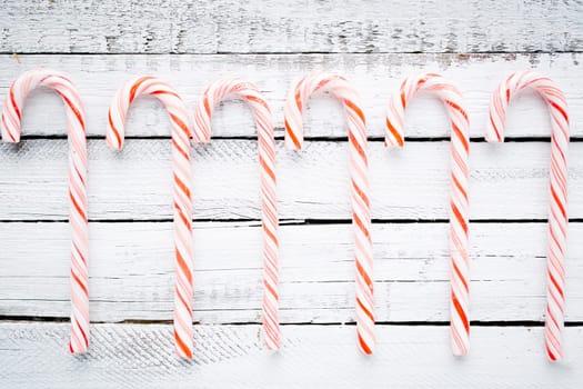 Striped candy canes over wooden background