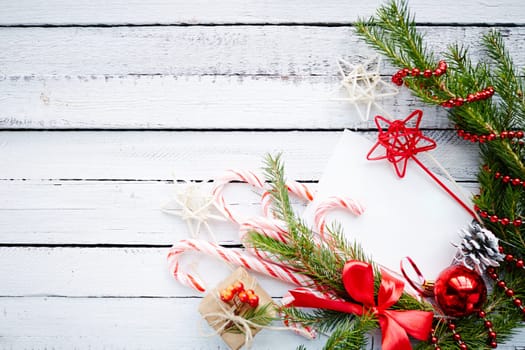 Composition of conifer branches, cones, decorative bubble, stars, beads, candy canes and small giftbox on wooden background