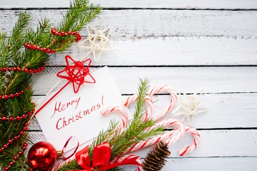 Christmas decorations and greeting card with regards on white wooden background