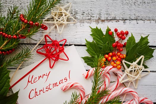 Christmas canes, decorations and greeting card on painted wooden background