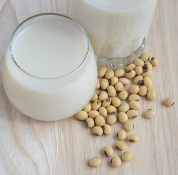 Fresh Soy milk (Soya milk) and dried soybean seeds on wooden background. Traditional staple of East Asian cuisine