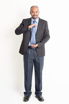 Full body mature Indian business man with cupped hands as if holding something, standing on plain background.