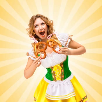 Happy excited sexy Oktoberfest woman wearing a traditional Bavarian dress dirndl holding two pretzels on colorful abstract cartoon style background.