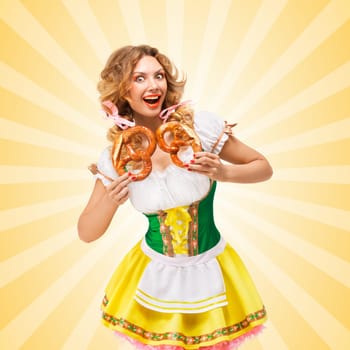 Happy excited sexy Oktoberfest woman wearing a traditional Bavarian dress dirndl holding two pretzels on colorful abstract cartoon style background.