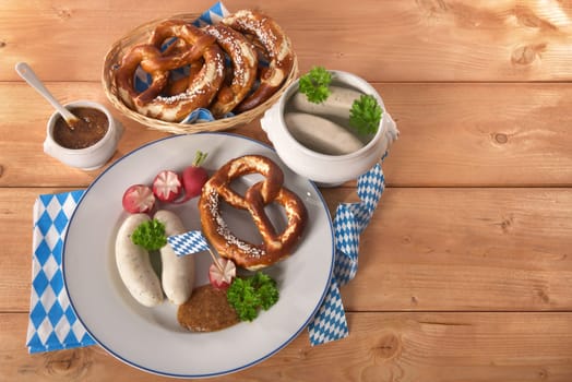 White sausage breakfast with sausages,pretzels and sweet mustard on wood substrate