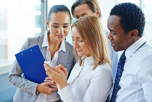 Businesswoman with cellphone and her colleagues reading sms