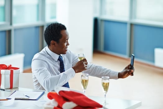 Businessman with champagne making selfie on Christmas eve in office
