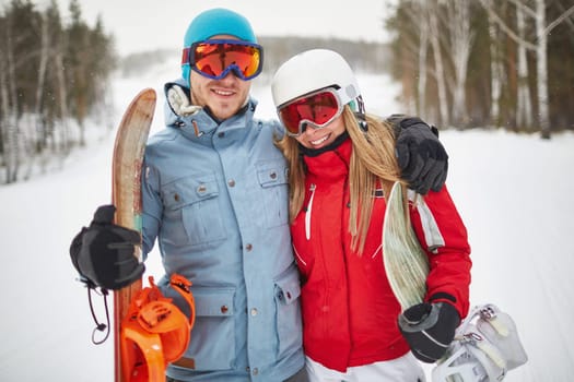 Couple of young snowboarders spending vacation on winter resort