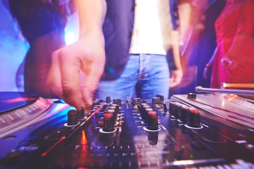 Hand of male dj adjusting sound during disco party