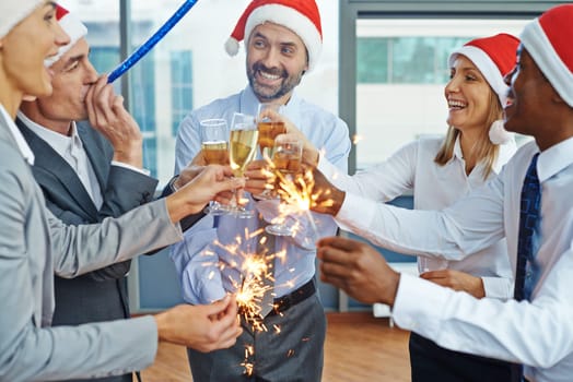 Happy colleagues in Santa caps having Christmas fun while toasting with champagne at party in office