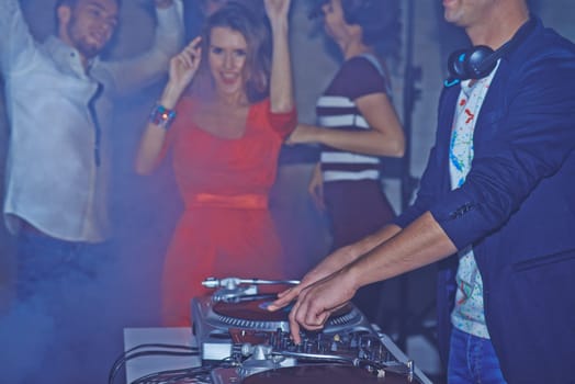 Male deejay adjusting sound on background of dancing friends
