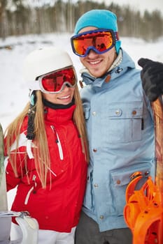 Couple of happy snowboarders in winter activewear looking at camera on resort