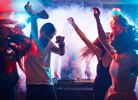 Young energetic people dancing by turntables of dj