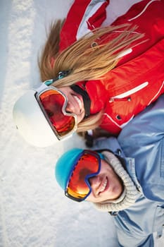 Affectionate couple in winter sportswear lying on snow