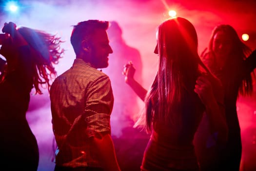 Happy couple and their friends dancing in disco club