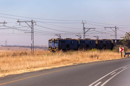 Railway train cargo coaches travel through dry season rural landscape