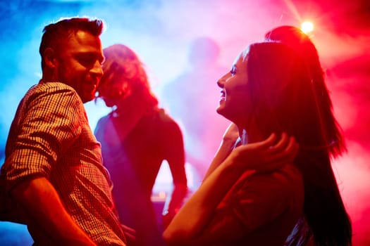 Happy young couple dancing at party in disco club