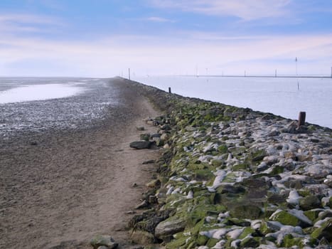 View over a rocky protective wall towards the horizon at the harbour entrance of Bensersiel / East Frisia in Germany