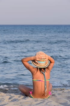 Little girl on the beach at sunset, portrait smiling with a large hat.