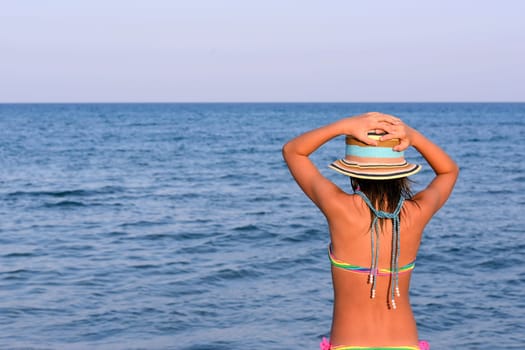 Little girl on the beach at sunset, portrait smiling with a large hat.