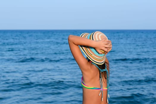 Little girl on the beach at sunset, portrait smiling with a large hat.