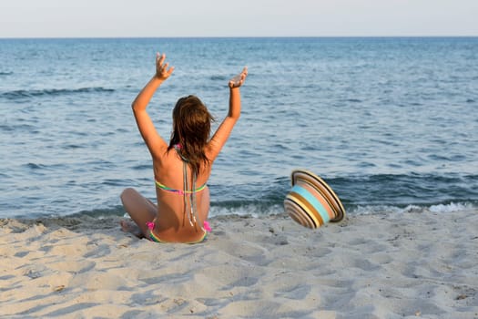 Little girl on the beach at sunset, portrait smiling with a large hat.