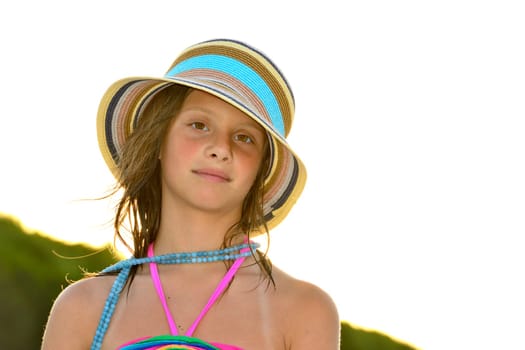 Little girl on the beach at sunset, portrait smiling with a large hat.